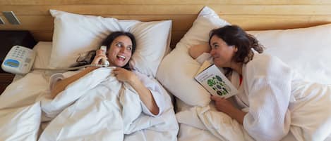 Dos personas acostadas en la cama, una sosteniendo un libro y la otra un teléfono.