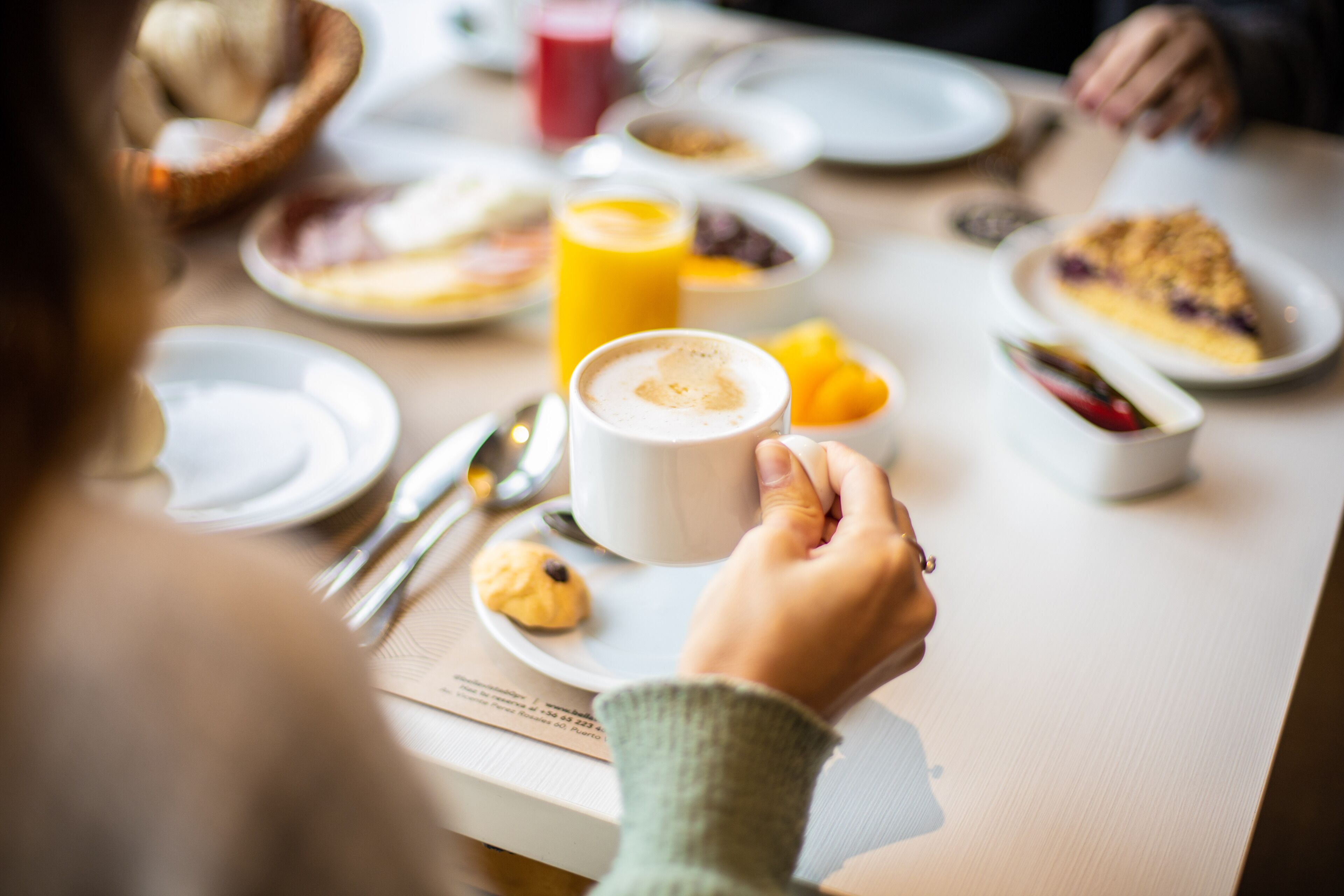 A breakfast setting with plates of food, a glass of orange juice, and a cup of coffee.