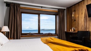 Une chambre d’hôtel avec un grand lit, une vue sur la montagne et un bureau avec une chaise.