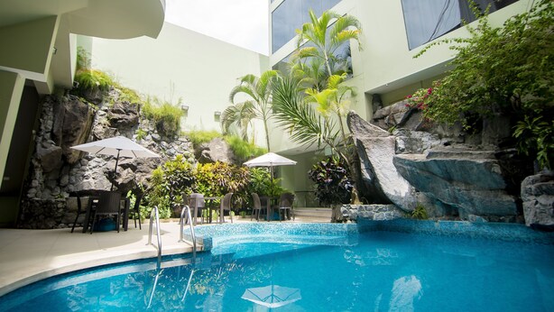An indoor swimming pool with a rock wall, seating area, and umbrellas.