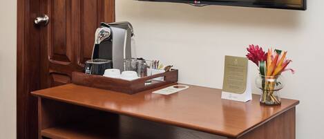 A wooden reception desk with a coffee machine, a glass, and a vase with flowers.