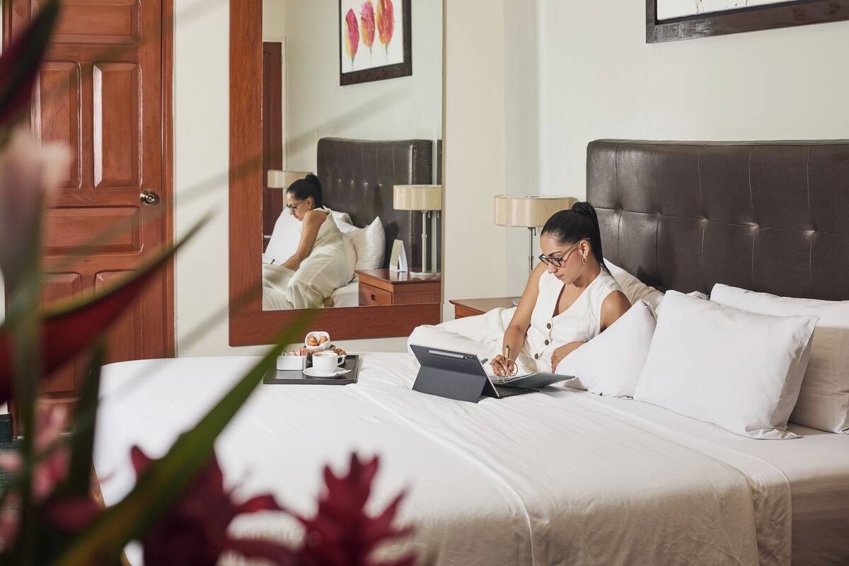Ein Hotelzimmer mit einem Bett, einem Laptop, einer Tasse und einem Tablett mit Gebäck.