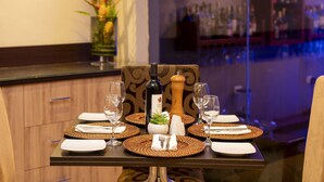 A dining table set with plates, cutlery, and wine glasses, with a bottle and salt shaker in the center.