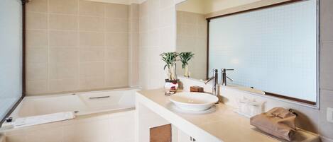 A modern bathroom with a bathtub, a sink, and a large mirror.