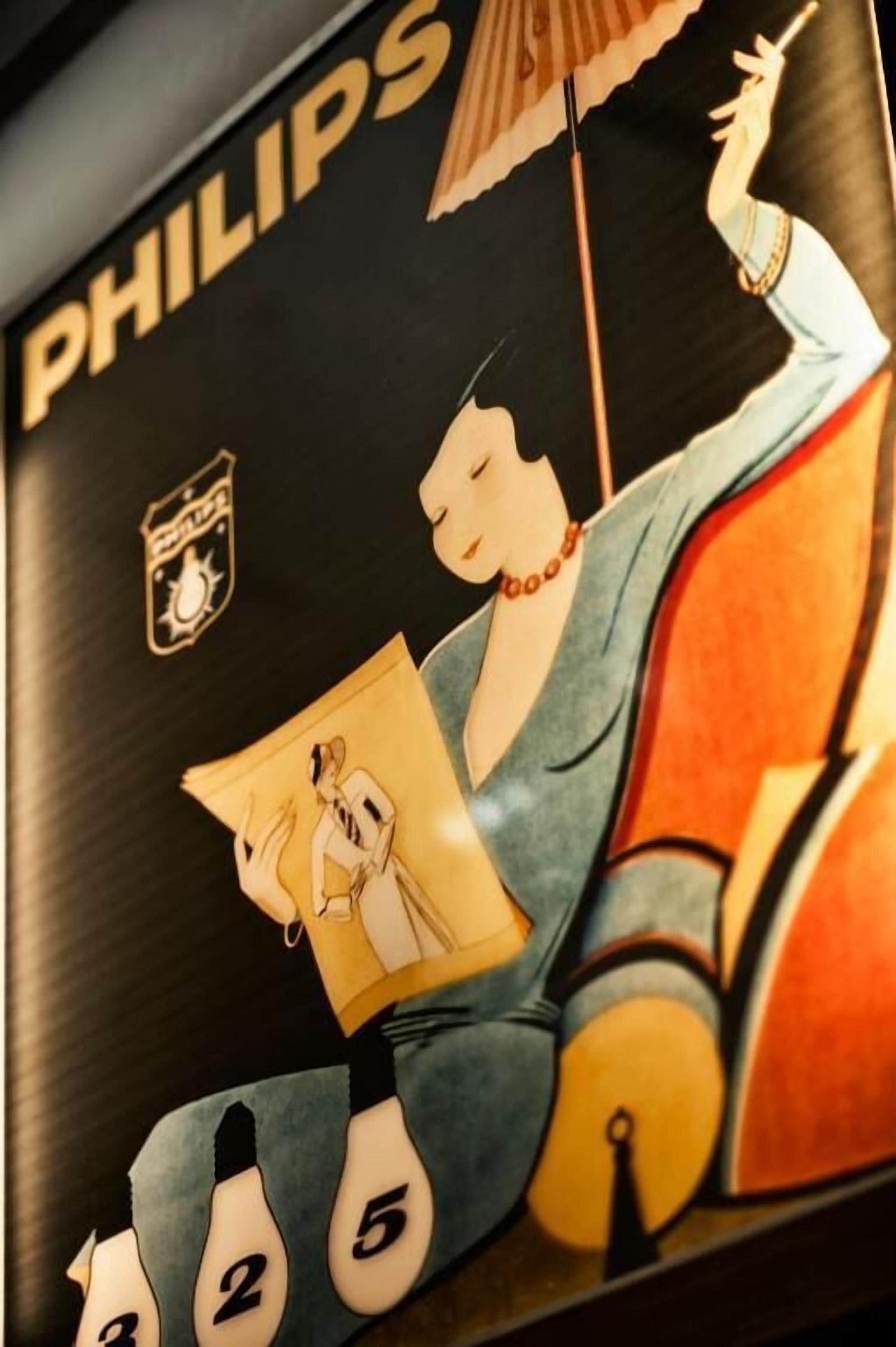 Un mur orné d’un grand logo Philips et d’une illustration stylisée représentant une personne en train de lire un livre.