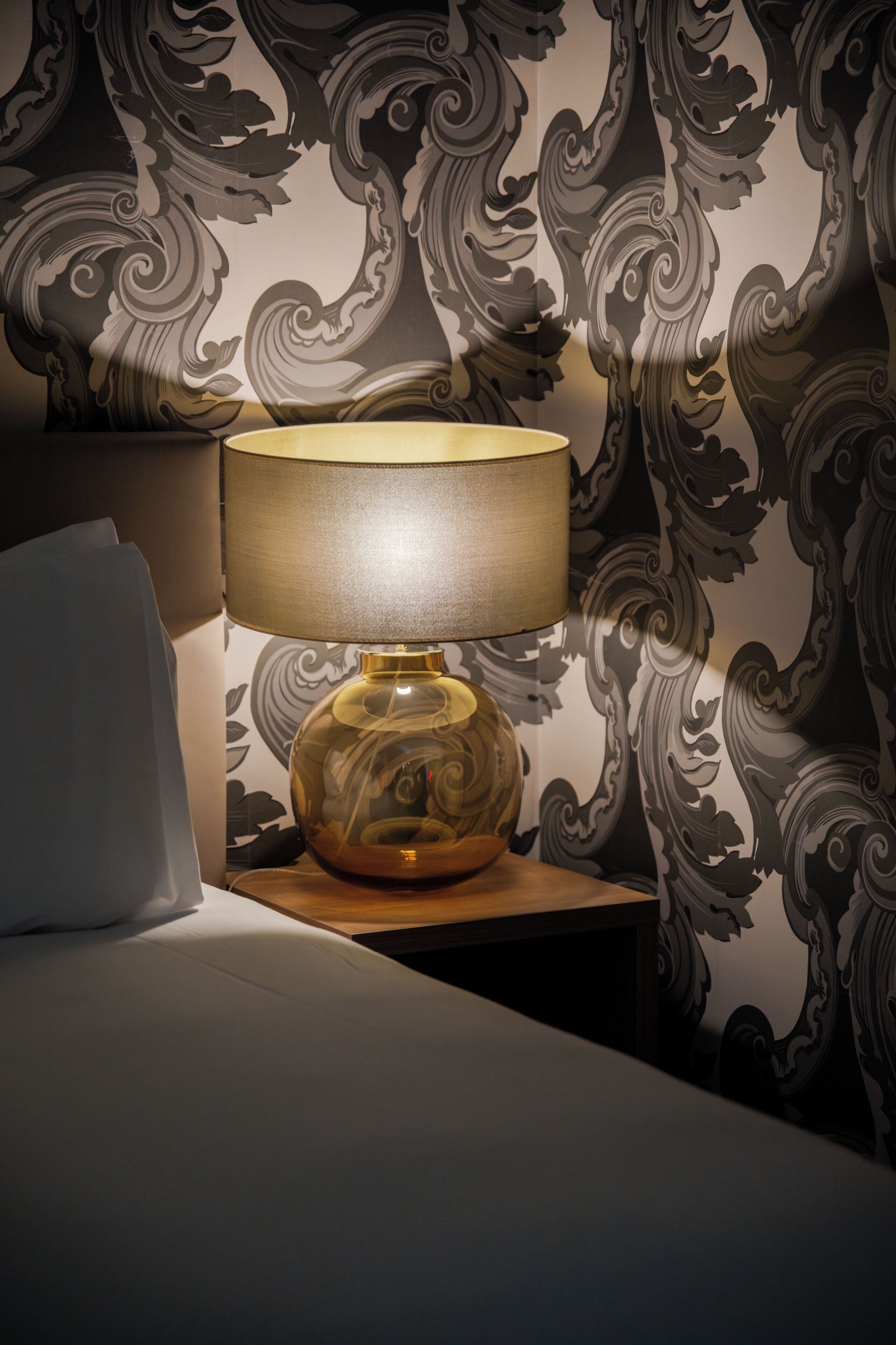 Una lampada su un comodino con carta da parati decorata.