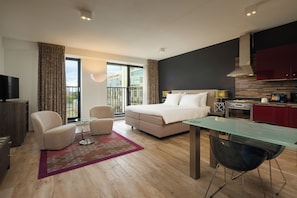 A modern hotel room with a bed, seating area, kitchenette, and a balcony with a city view. - Westcord Hotel Eindhoven (Eindhoven)