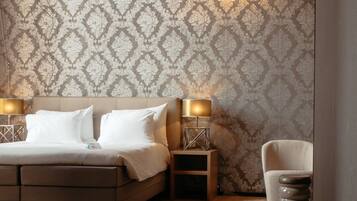 A bedroom with a bed, two bedside tables, a chair, and a patterned wallpaper.