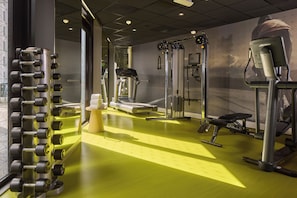 A gym with exercise equipment, a treadmill, and a wall-mounted TV. - Westcord Hotel Eindhoven (Eindhoven)