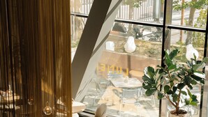 A modern interior with a dining area, large windows, and a view of the street. - Westcord Hotel Eindhoven (Eindhoven)