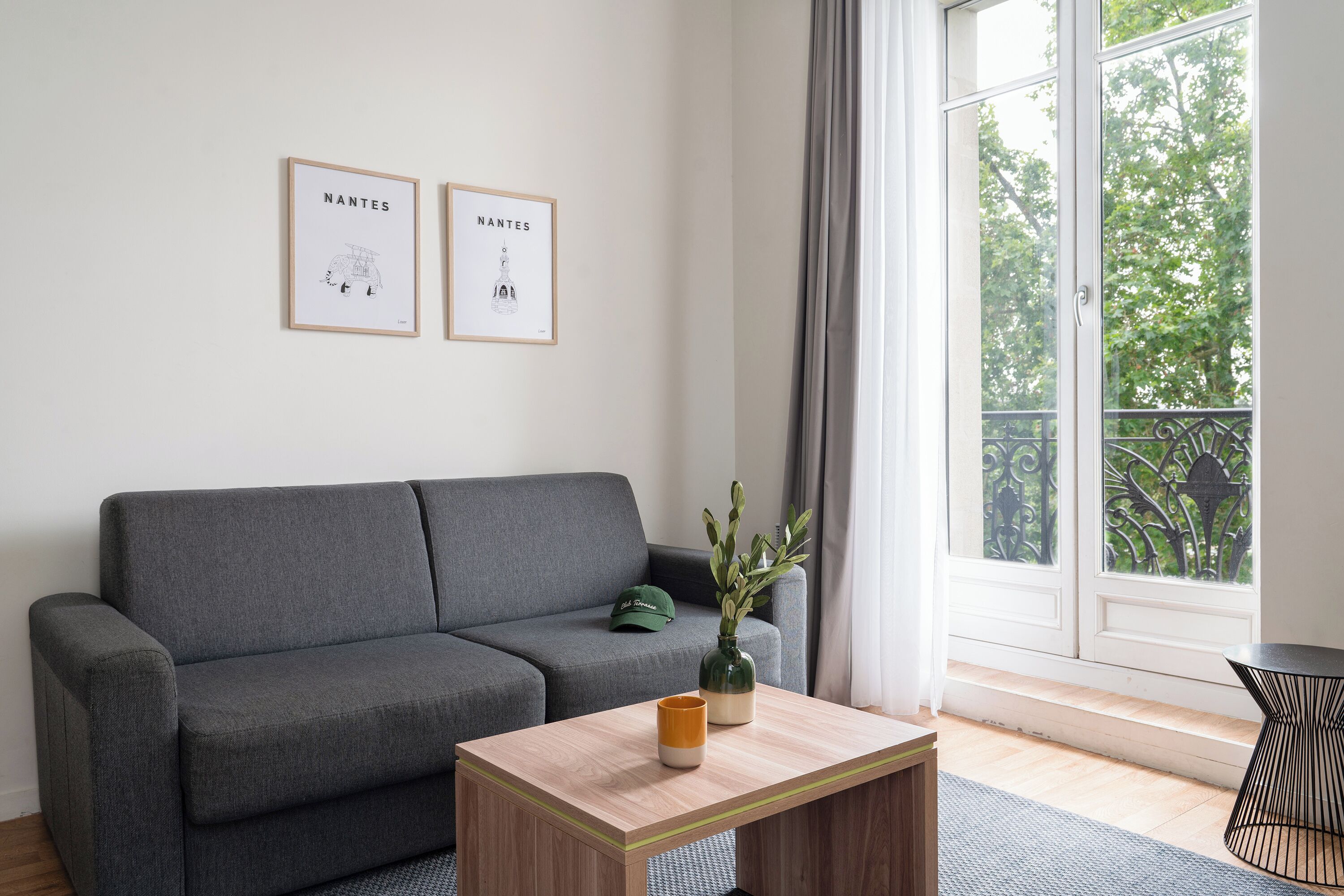 A modern living room with a grey sofa, a wooden coffee table, and two framed artworks on the wall.