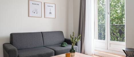 A modern living room with a grey sofa, a wooden coffee table, and two framed artworks on the wall.