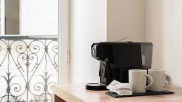 A coffee maker on a table with two white mugs and a napkin.