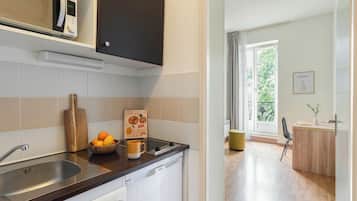A modern kitchen with a built-in microwave, a sink, and a wooden cutting board.