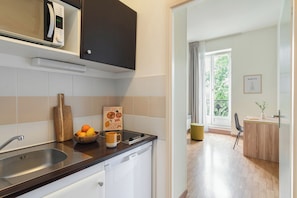 Une cuisine moderne équipée d’un four à micro-ondes encastré, d’un évier et d’une planche à découper en bois.