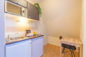 Une cuisine compacte équipée d’un four à micro-ondes, d’un évier et d’une petite table à manger avec une chaise.