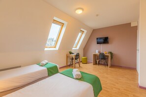 Une chambre d’hôtel avec deux lits, un bureau, une chaise, une télévision et une fenêtre.