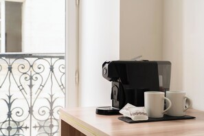 Una cafetera sobre una mesa con dos tazas blancas y una servilleta.