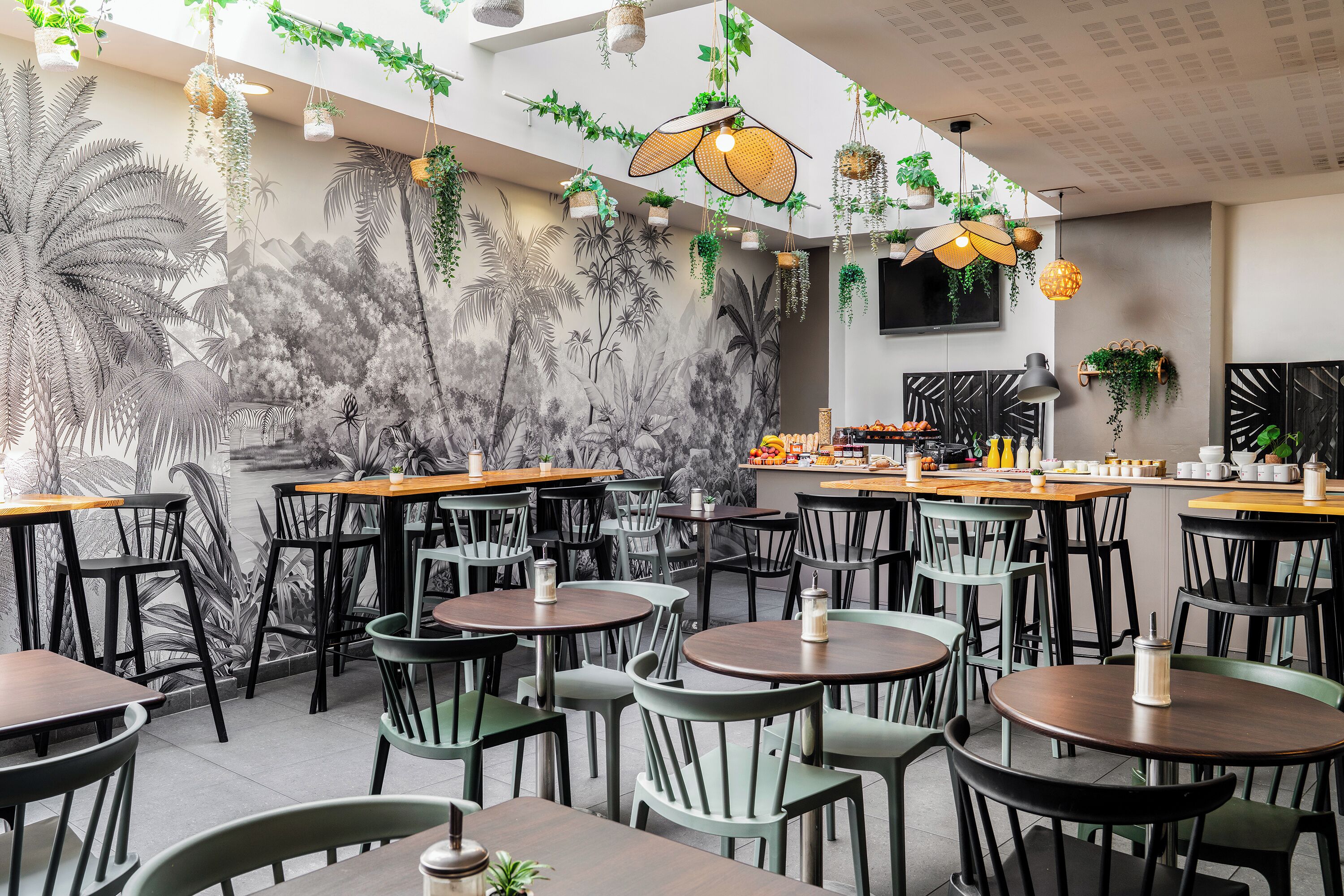 Interior de un restaurante con varias mesas y sillas, una zona de bar y un mural con una escena tropical.