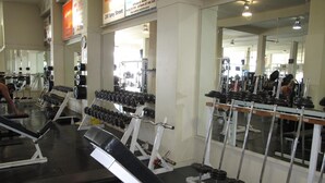 Un gimnasio con equipo de levantamiento de pesas, bancos y espejos.