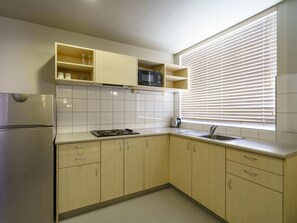 Eine Küche mit Kühlschrank, Herd, Spüle und Fensterläden.
