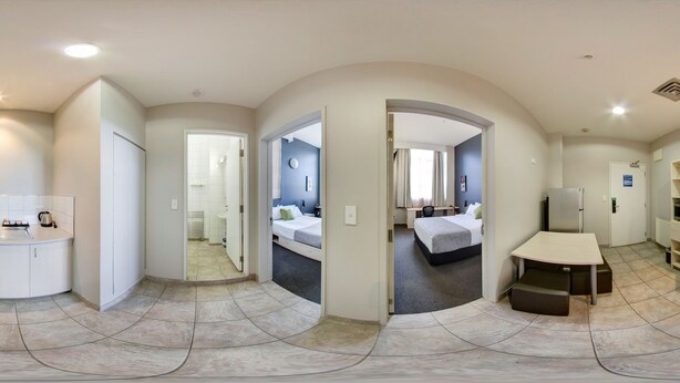 Una vista panorámica de una habitación de hotel moderna con kitchenette, un dormitorio separado y un comedor.
