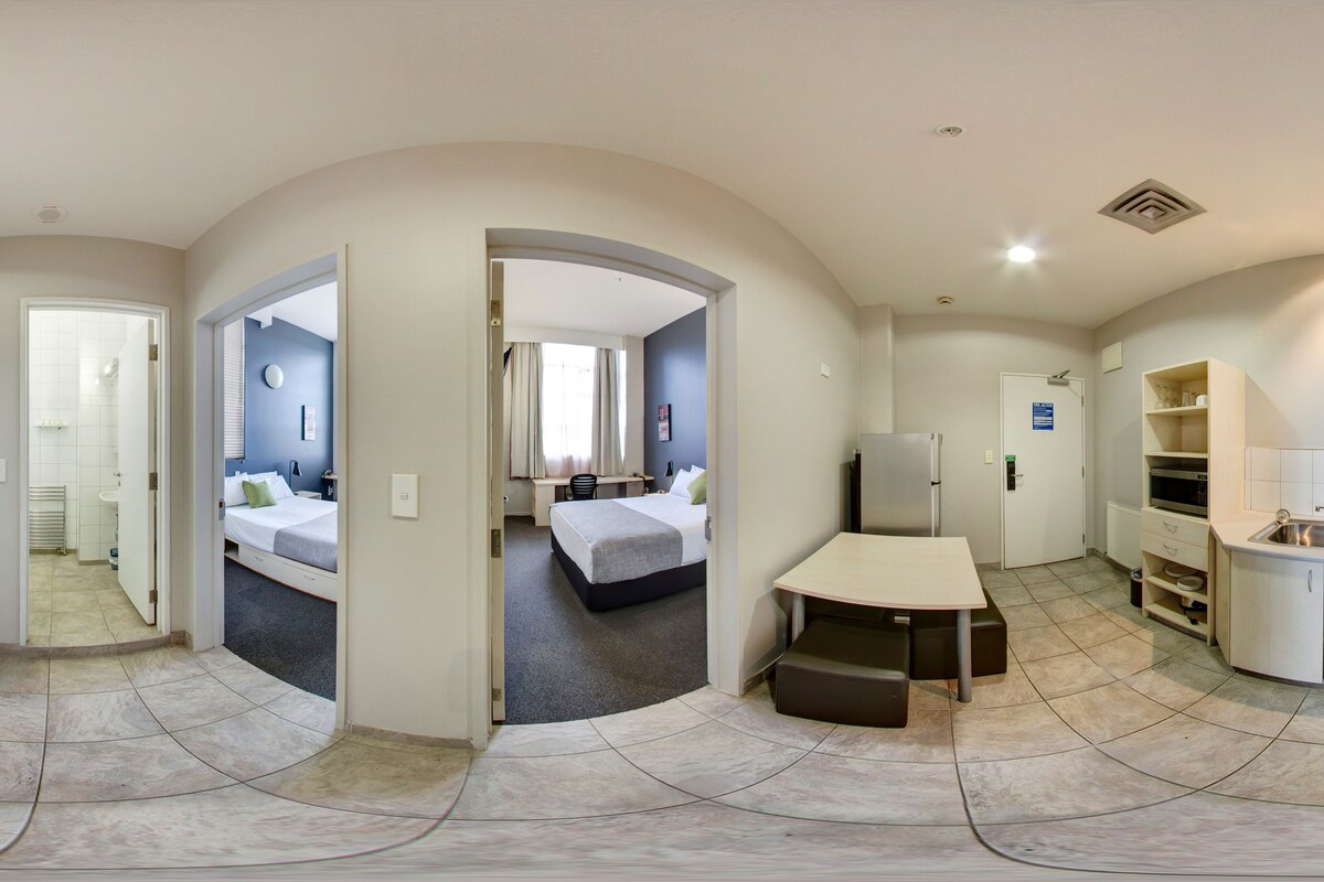 Una vista panorámica de una habitación de hotel moderna con kitchenette, un dormitorio separado y un comedor.