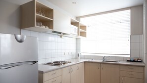 Una cocina moderna con armarios blancos, horno empotrado y ventana con persianas.