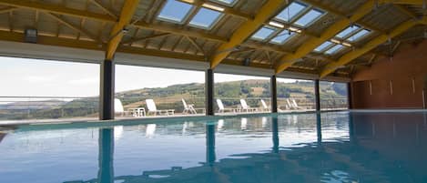 Una piscina techada, sillones reclinables de piscina