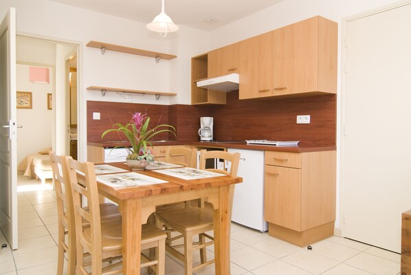 Una cocina compacta con armarios de madera, una mesa de comedor con sillas y una cafetera.