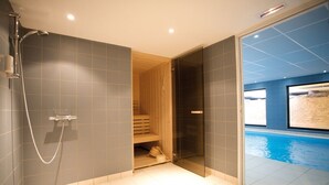 A modern bathroom with a glass-enclosed shower, a wooden sauna, and a pool area. - Lagrange Apart'HOTEL Strasbourg Wilson (Strasbourg)