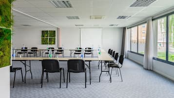 A conference room with a long table, black chairs, water bottles, and a projector screen.