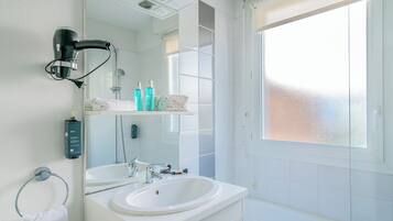 A modern bathroom with two sinks, a large mirror, a towel rack, and a window with frosted glass.