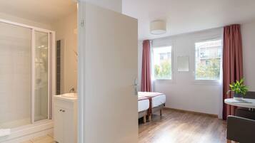 Een moderne badkamer met een douchecabine van glas, een witte wastafel en een toilet.