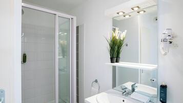 A modern bathroom with a glass shower enclosure, a white sink, and a mirror with integrated lighting.