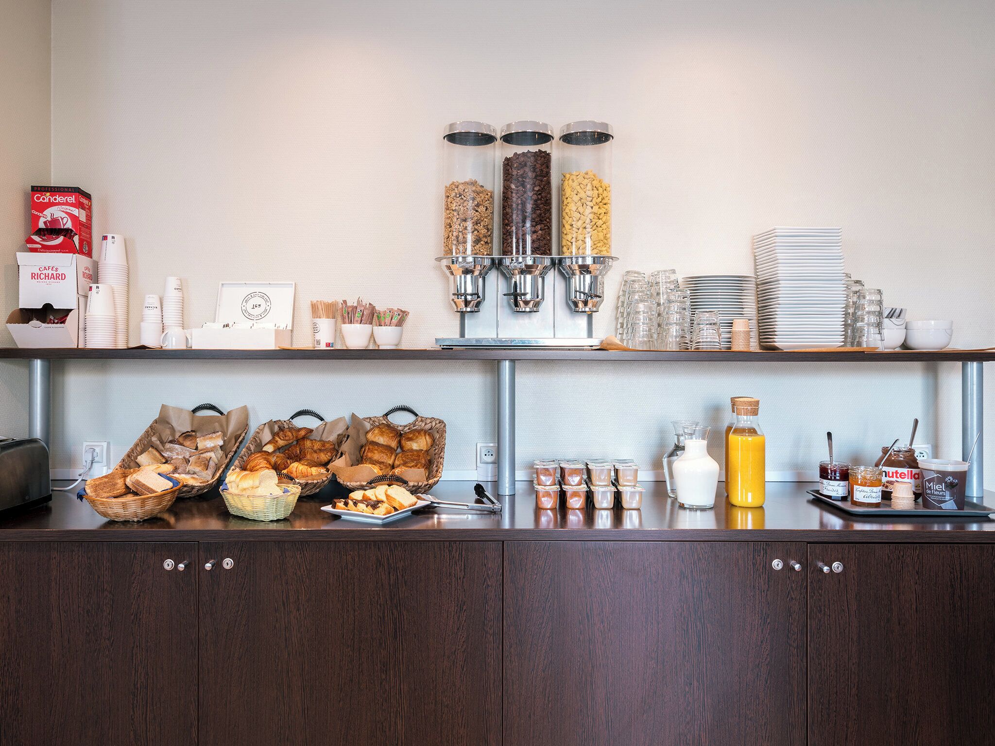 A breakfast buffet setup with various food items, condiments, and utensils.