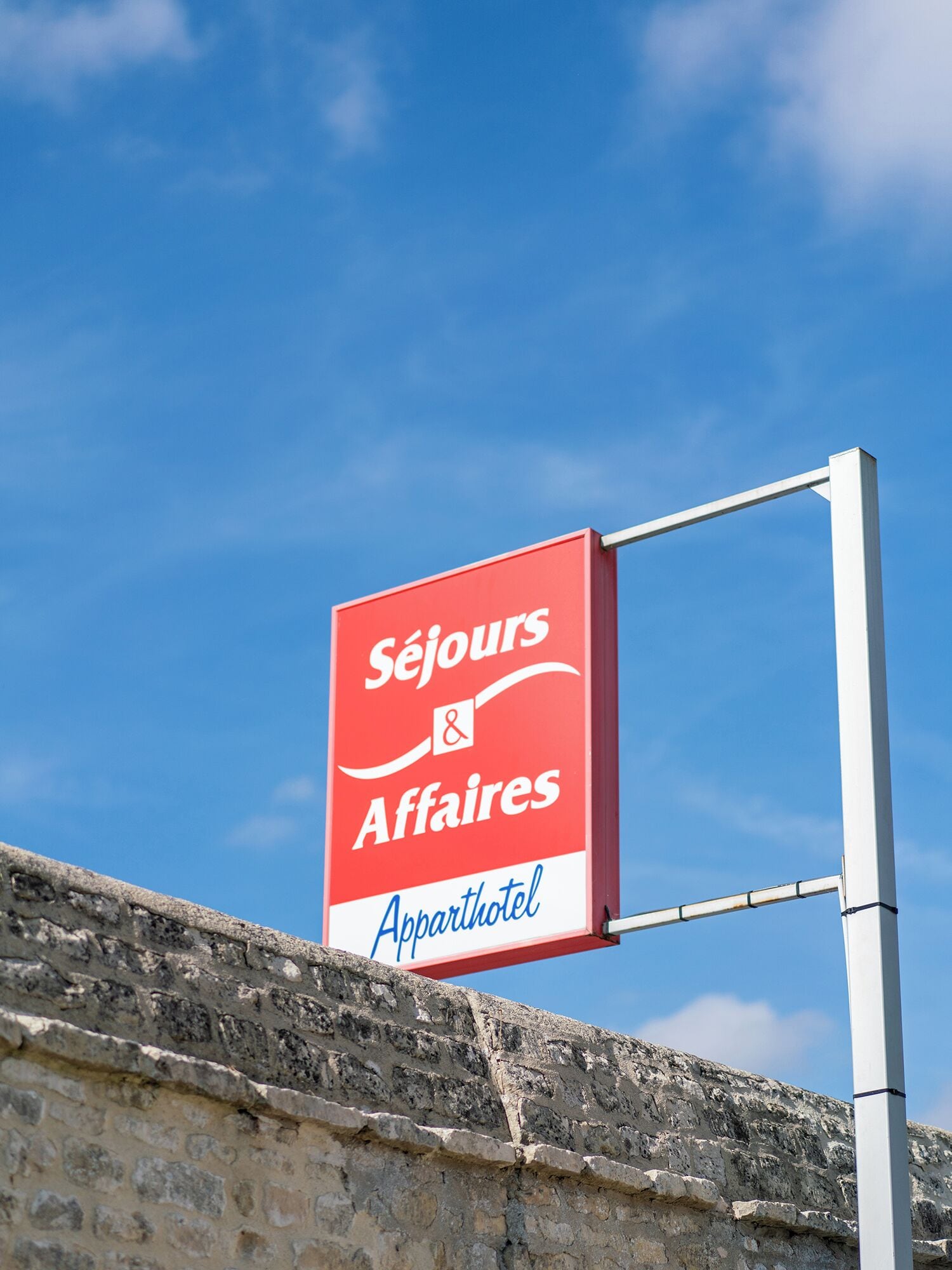 A sign for Séjours Affairs & Apparithotel against a clear blue sky.