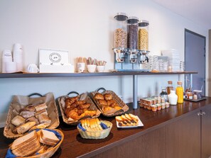 A buffet setup with various food items, including bread, pastries, and beverages. - Séjours & Affaires Caen Le Clos Beaumois (Caen)