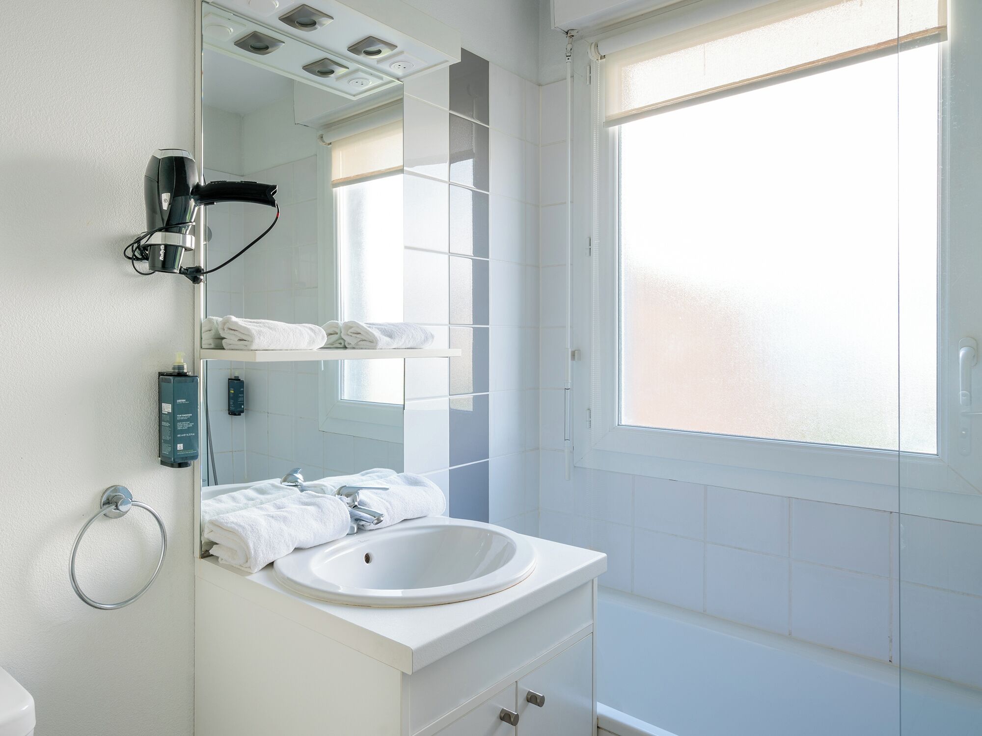 A modern bathroom with a white sink, a mirror, and a towel rack.