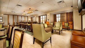 Un hall d’hôtel comprenant un espace repas, des coins salon et un téléviseur.