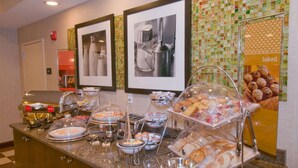 Un buffet proposant une variété de plats, notamment du pain et des viennoiseries, ainsi qu’un coin café.