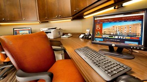 Une chambre d’hôtel avec un bureau en bois, un ordinateur et un fauteuil de bureau orange.