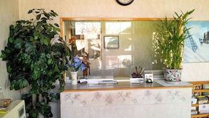 A reception desk with a mirror, a potted plant, and a small American flag. - Relax Inn Westminster (Westminster)