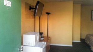 A compact room with a microwave on a small table, a lamp, and a bed. - Relax Inn Westminster (Westminster)