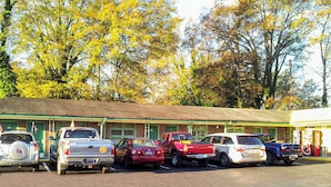 A row of parked vehicles in front of a building with a green roof and brick walls. - Relax Inn Westminster (Westminster)