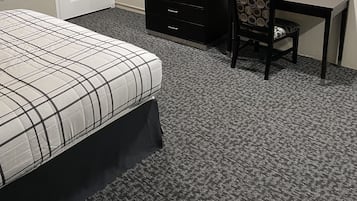 A hotel room with a bed, a desk, a television, and a chair.