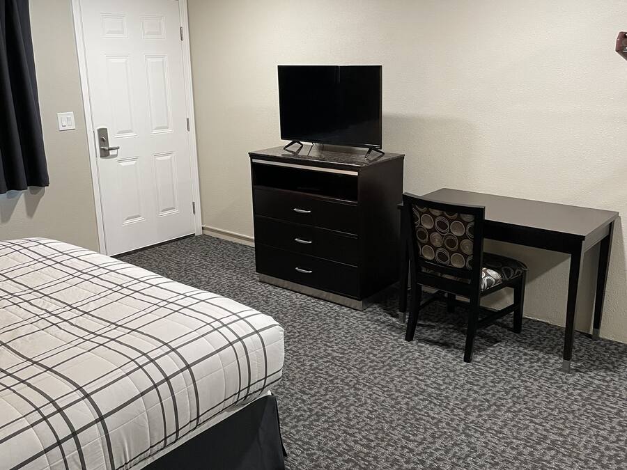 A hotel room with a bed, a desk, a television, and a chair.