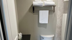A bathroom with a toilet, a trash can, a towel rack, and a toilet paper holder.