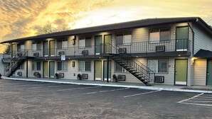 A motel with multiple floors, outdoor parking, and a staircase leading to the entrance.