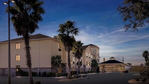 A hotel with a parking lot, palm trees, and a well-lit entrance. - Comfort Suites (Panama City)